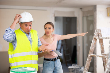 Portrait of perplexed man builder and annoyed gesturing woman, conflict between female architect...
