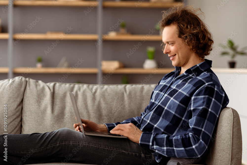 Poster freelance. side view of freelancer guy using laptop working remotely online sitting on couch at home