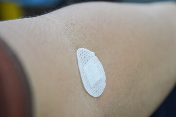 a white tape that sticks to a man's arm after taking blood for a blood test
