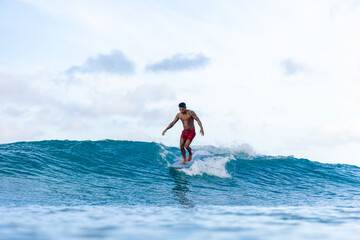 A man is surfing on a wave and walks towards the nose of his board.