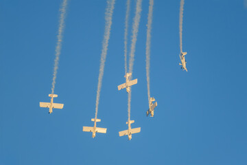 Stunt aerobatic planes performing stunts in blue sky with smoke trail. Concept of teamwork, collaboration, coordination, trust, precision, difficulty, challenge, speed, synergy