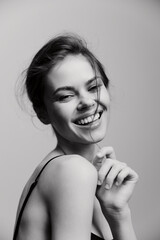 Joyful young woman smiling brightly, showcasing confidence with playful expression, against soft...
