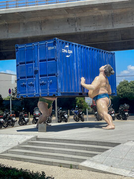 Marseille, France on May 22, 2024: The "Takes Two to Tango Sculpture" of two sumo wrestlers lifting a CMA-CGM shipping container.
