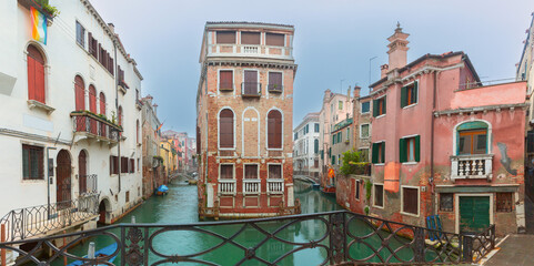 Calm Venetian canal surrounded by historic buildings under cloudy sky, Venice, Italy