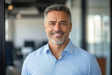 Obraz premium Confident Middle Aged Businessman Smiling in Modern Office Portrait