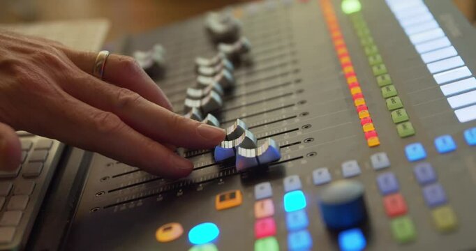A hand operates a fader on a mixer in the recording studio