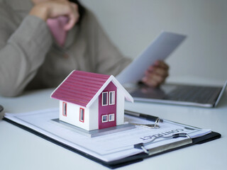 Fototapeta premium Beautiful real estate agent signs documents and gives home insurance advice Create a home purchase insurance contract to approve the purchase for the customer