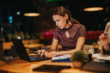 A dedicated businesswoman concentrates on her laptop while participating in a late-night meeting, emphasizing focus and productivity in a modern workplace setting.