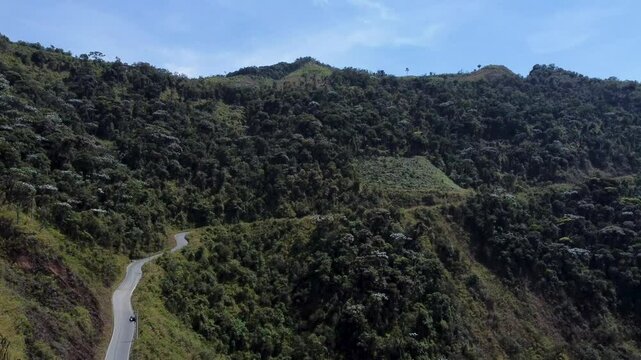 Drone descends curvy road on mountainside, lush green landscape in mountain range between Guaranda and Montalvo, Ecuador