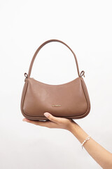 Women's luxury handbag in girl's hand, brown handbag purse, leather bag isolated on white background