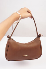 Women's luxury handbag in girl's hand, brown handbag purse, leather bag isolated on white background