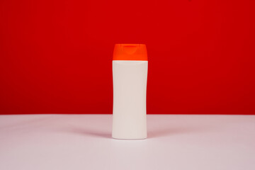 Plastic shampoo bottle with flip-top lid isolated on red and white background. MockUp template for your design. Empty and clean packaging for cosmetic product. File contains clipping path.
