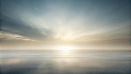 Obraz premium A hazy, ethereal sunrise casts a soft glow over a vast expanse of still water. The sky, painted in shades of muted blue and golden yellow, reflects the tranquil beauty of the moment.
