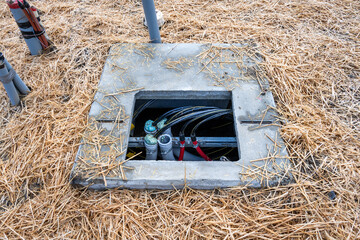 New underground cement equipment vault top open and pipes and wire cable running through it, fresh...