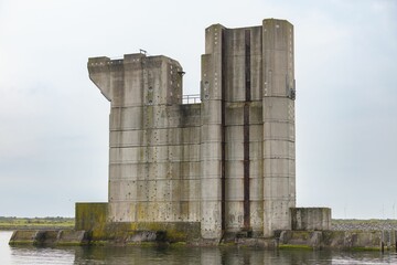 Abandoned concrete structure with a wind turbine in the background under a clear sky