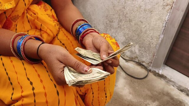 An Indian female counting 500 rupees Indian currency notes.
