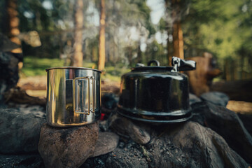 mug and kettle near campfire