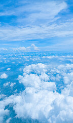 Aerial view of fluffy white clouds, captured from an airplane at high altitude. Scene for advertising, travel, aviation, exploration, nature, meteorology. Beautiful blue sky background