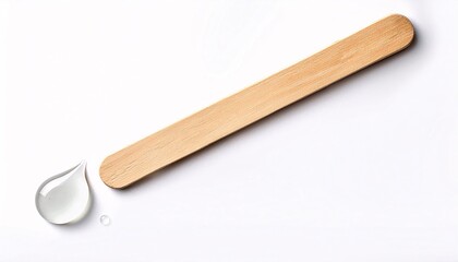 Obraz premium A wooden tongue depressor lying flat with a small drop of throat examination gel beside it