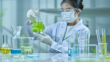 The front view of the photo, shows a flask with a tea tree solution being observed by a researcher...