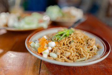 A colorful noodle dish served with fresh vegetables and tender, juicy chicken pieces