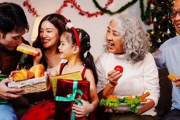 Parents, children, and grandparents gather at home for a joyful Christmas and New Year celebration, also marking the granddaughter’s birthday. They share wine, food, drinks, and exchange gift boxes