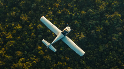 Aerial top down view of a small white single propeller flying over a green lush forest creating a green natural backdrop , exploration and travel concept image