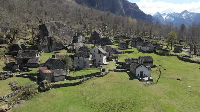 Ancient village showcasing charming stone houses nestled amidst a picturesque natural landscape in the swiss alps, Sabbione. Ticino, Switzerland, drone orbiting shot