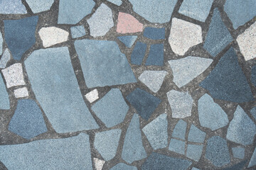 A close-up of a mosaic-like pattern with irregularly shaped tiles in shades of blue, white, and pink. The tiles fit together like a jigsaw puzzle, creating a visually appealing texture