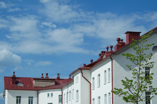 Facade of a white house with a red roof against the sky