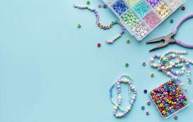 Colorful assortment of beads and jewelry-making tools on a blue surface with completed bracelets