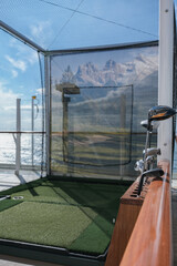 Golf tee shot simulator on outdoor sports deck of modern luxury ocean liner cruiseship cruise ship...
