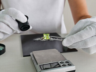 A skilled gemologist conducts an assessment of a vibrant green gemstone using a loupe