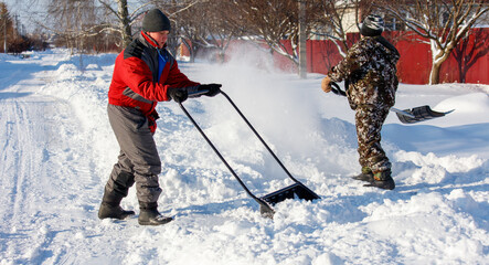 Two people are shoveling snow with a snow plow © schankz