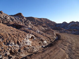 dirt road in Moon Valley desert in Atacama, Chile. Scenic landscape with desertic rocks in morning light. Barren and dry scenery in South America