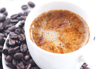 エスプレッソに牛乳をたっぷり入れたコーヒー、カフェ・ラッテと、深煎りしたコーヒー豆
