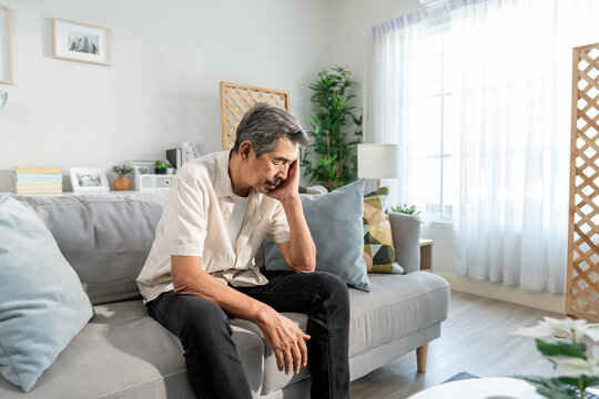 Asian senior elderly depress man sitting alone in living room at home.