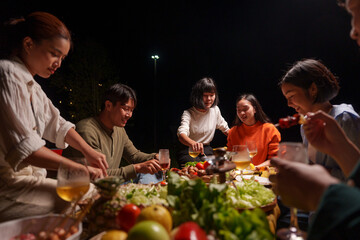 Group of young Asian friends enjoying dinner party together Barbecue grilling, drinking beer, people, food, healthy fruits and vegetables, celebrating, lifestyle drinks. New Year celebration concept.