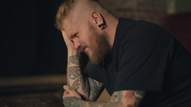 Feel headache, adult male person sitting alone home in evening, holding head. Bad feeling and tiredness, overtime work and troubles with health, brawny man with beard feeling pain in head, problems