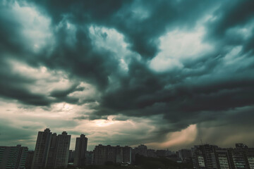 Obraz premium Dark storm clouds over city skyline at sunset creating dramatic atmosphere