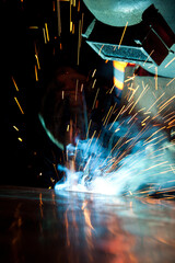 Welder uses torch to make sparks during manufacture of metal equipment, industrial professional...