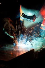 Welder uses torch to make sparks during manufacture of metal equipment, industrial professional...