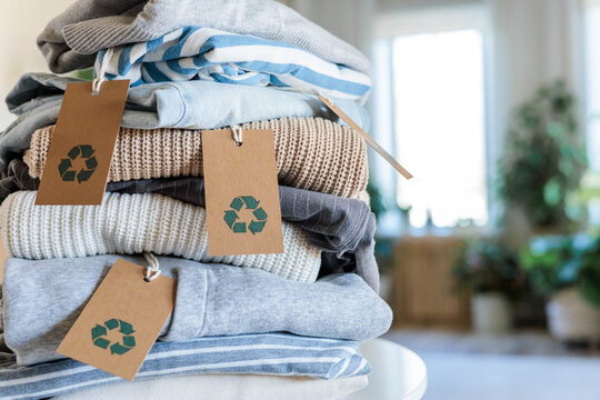 Pile of neatly folded clothes made by recycling material with tag on table top view closeup