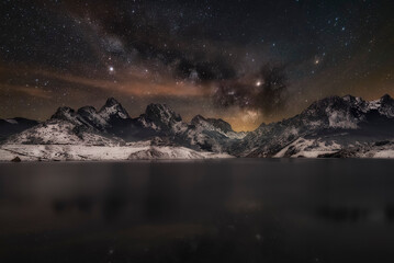 Fototapeta premium View of the town of Riaño, Leon, covered in snow at night with the reservoir and mountains in the background