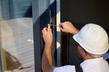 Construction worker installing door in a new house construction site. Man in working attire install...