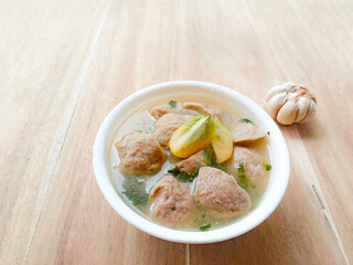 meatball soup served in a white bowl on a wooden background. bowl with yummy meatball soup. warm...