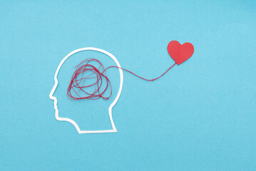 Silhouette of head with tangled red thread connecting to heart symbolizing mental and emotional...