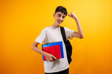 Teenage student holding books, showing his strong arm.