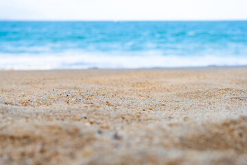 Close-up view of a sandy beach with a blurred turquoise sea in the background. The central part of...
