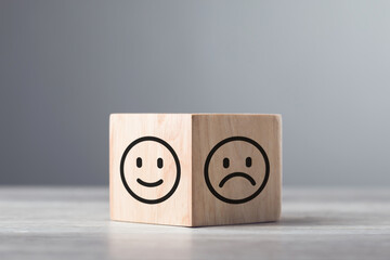 Wooden blocks displaying a sad face transitioning to a happy face, symbolizing a shift from negativity to positivity. Final block turns from sad to happy, highlighting the power of a positive outlook